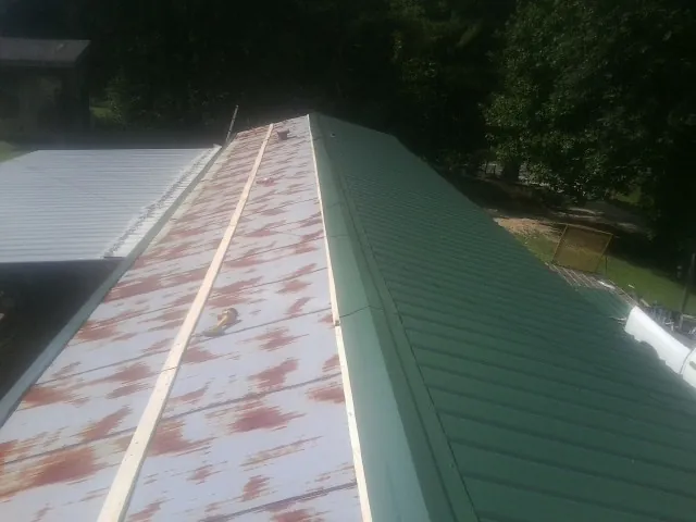 Old rusted panels beside newly installed green metal roofing — Wind Damage Roof Repair by Roofing Brothers in Paoli