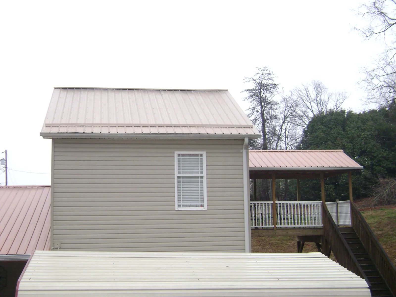 Tan metal roofs on a two story addition and attached porch, from a Roof Replacement job in Paoli
